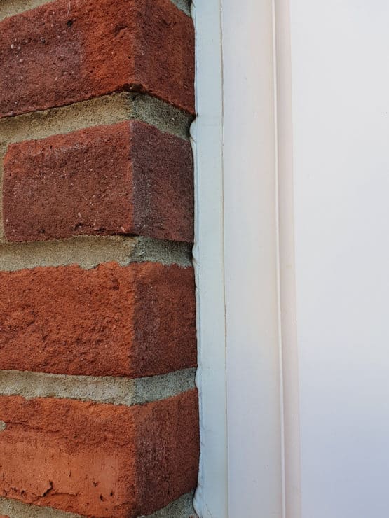 A very close up view of a thin UPVC door frame panel, with a brick wall to the left which would block lots of a wide-angle lens video capture.