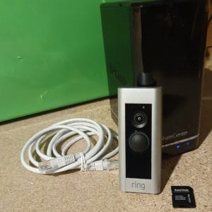 A Ring Doorbell Pro in-front of a D-Link ShareCenter NAS, and an SD-card adapter and Ethernet cable on the sides.