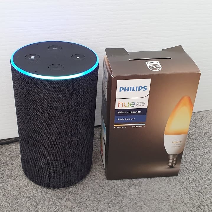 My Amazon Echo (with a blue ring, in listening mode) next to a Philips Hue E14 White Ambiance box.