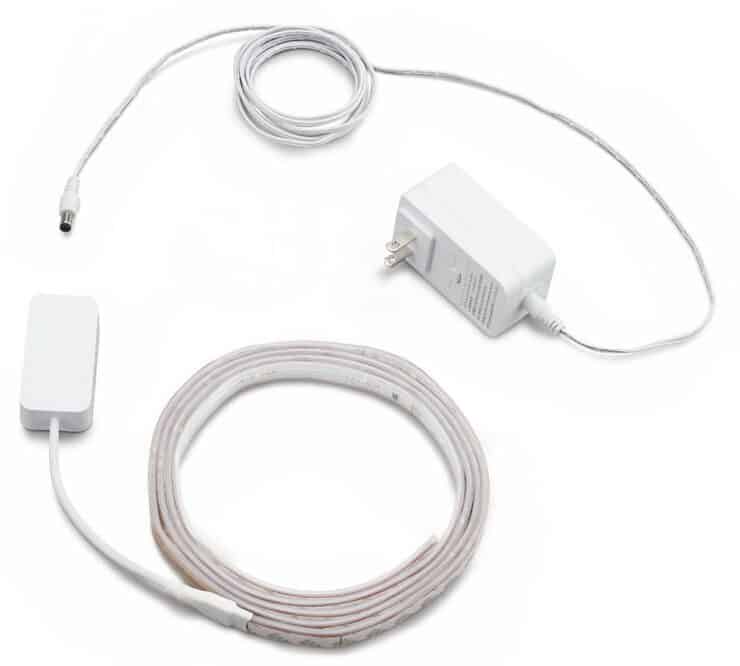 The contents of a Hue Lightstrip V3 Plus box, containing the lightstrip (which connects to a transformer), and a plug adapter (to plug in to the transformer).